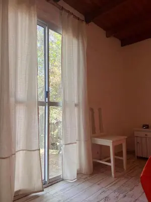 a room with a large window with curtains and a table at El paraíso de Tu Descanso in Villa de Las Rosas