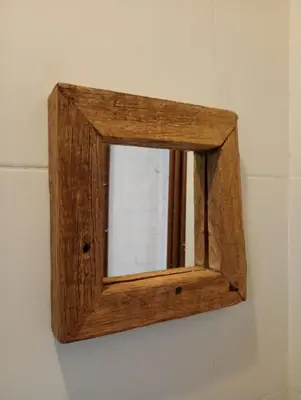 a wooden mirror hanging on a white wall at El paraíso de Tu Descanso in Villa de Las Rosas