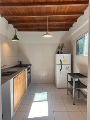 a kitchen with a white refrigerator and wooden ceilings at El paraíso de Tu Descanso in Villa de Las Rosas