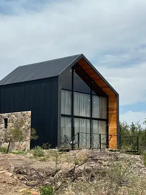 a black building with large windows on top of a field at Sauron Adventure in Cuesta Blanca