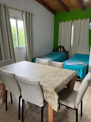 a dining room with a table and chairs and two beds at Monoambientes comechingones in Villa Cura Brochero