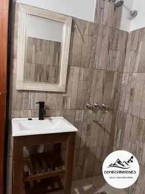 a bathroom with a sink and a mirror and a shower at Monoambientes comechingones in Villa Cura Brochero