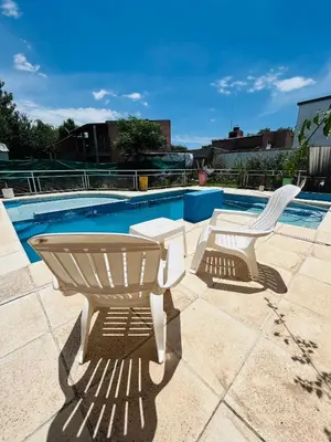 two white chairs sitting next to a swimming pool at Monoambientes comechingones in Villa Cura Brochero