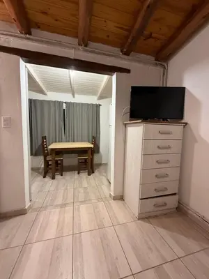 a dining room with a table and a tv on a dresser at Monoambientes comechingones in Villa Cura Brochero