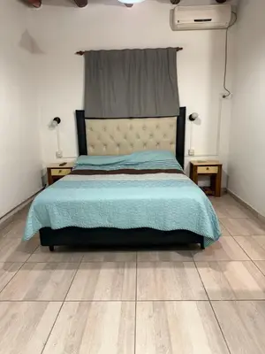 a bedroom with a bed with a blue comforter and two lamps at Monoambientes comechingones in Villa Cura Brochero