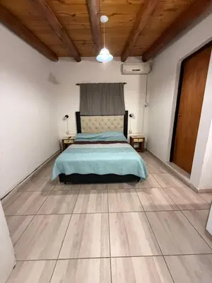 a bedroom with a bed and a wooden floor at Monoambientes comechingones in Villa Cura Brochero