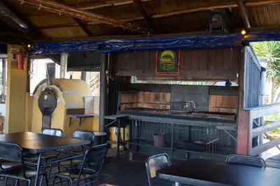 a restaurant with tables and chairs and a kitchen at Parada 14 in Cavalango