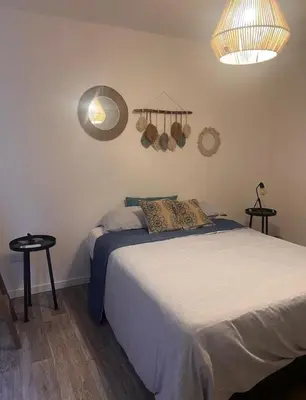a bedroom with a bed and two tables and a mirror at Vive Carlos Paz in Villa Carlos Paz