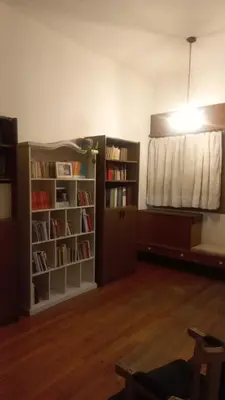 a room with bookshelves and a bed and a window at Casa Corna in Río Cuarto