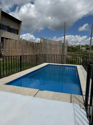 a blue swimming pool in front of a fence at Cabaña El Bosquecito in Estancia Vieja