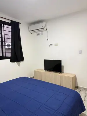 a bedroom with a blue bed and a television at Cabaña El Bosquecito in Estancia Vieja