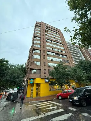 a tall building on a city street with parked cars at Departamento alquiler temporal Nueva Cordoba in Cordoba