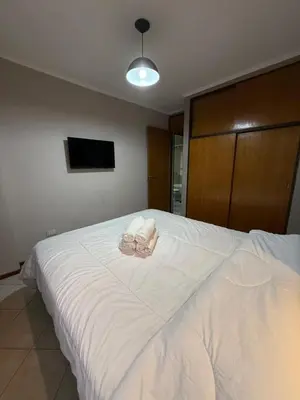 a bedroom with a large white bed with a tv at Departamento alquiler temporal Nueva Cordoba in Cordoba