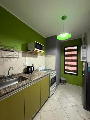 a green kitchen with a sink and a microwave at Departamento alquiler temporal Nueva Cordoba in Cordoba
