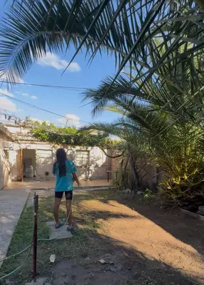 a woman is standing under a palm tree at Casa pleno centro Villa Dolores in Villa Dolores
