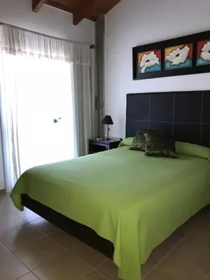 a bedroom with a large green bed with a window at Complejo Soles de Oro in Villa Icho Cruz
