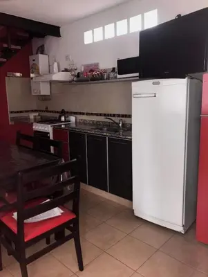 a kitchen with a white refrigerator and a table at Complejo Soles de Oro in Villa Icho Cruz