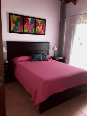 a bedroom with a large bed with a pink blanket at Complejo Soles de Oro in Villa Icho Cruz