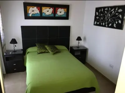 a bedroom with a green bed and two night stands at Complejo Soles de Oro in Villa Icho Cruz