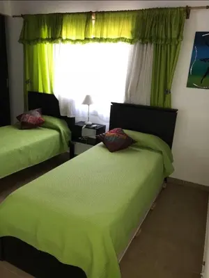 a bedroom with two beds with green sheets and a window at Complejo Soles de Oro in Villa Icho Cruz