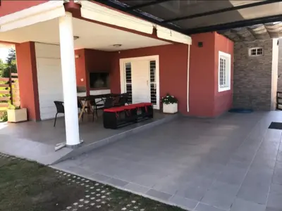a patio with a red house with a table at Complejo Soles de Oro in Villa Icho Cruz