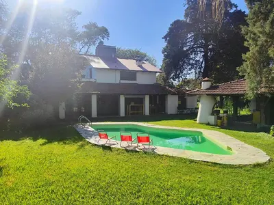 a swimming pool with two chairs and a house at Casa Mudita in Cordoba