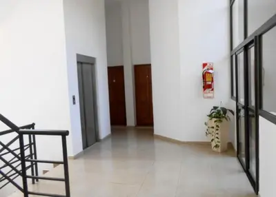 a hallway with white walls and a chair and a plant at Edificio Panorámico in Villa Carlos Paz