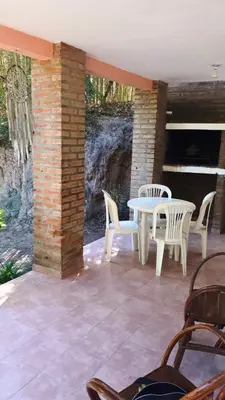 a patio with white chairs and a table and a stone wall at Dúplex el descanso in Villa Anizacate