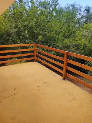 a wooden fence with trees in the background at Dúplex el descanso in Villa Anizacate