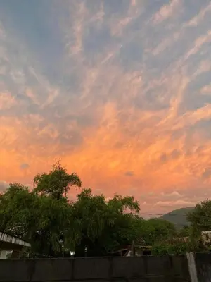 a cloudy sky at sunset with trees in the foreground at Depto Dos Plantas en Bialet Massé in Bialet Massé