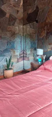 a bedroom with a red bed and a stone wall at Cabaña tierra de sueños in Santa Rosa de Calamuchita