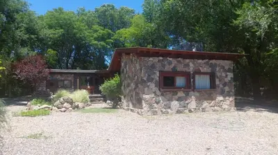 a small stone house in front of a forest at Cabaña tierra de sueños in Santa Rosa de Calamuchita