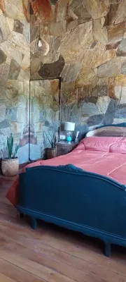 a bed in a room with a stone wall at Cabaña tierra de sueños in Santa Rosa de Calamuchita
