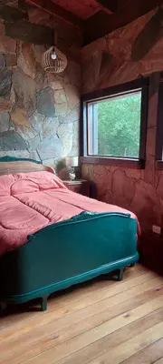 a bedroom with a large bed with a stone wall at Cabaña tierra de sueños in Santa Rosa de Calamuchita