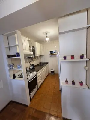 a kitchen with white cabinets and a stove top oven at Cómodo departamento en Nueva Córdoba in Cordoba