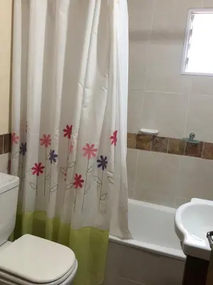 a bathroom with a toilet and a shower curtain with flowers at La Casa de Juan in San Antonio de Arredondo