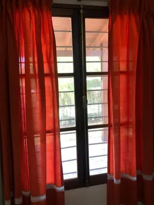 two windows with red curtains in a room at La Casa de Juan in San Antonio de Arredondo