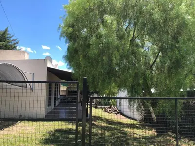 a fence in front of a house with a tree at La Casa de Juan in San Antonio de Arredondo