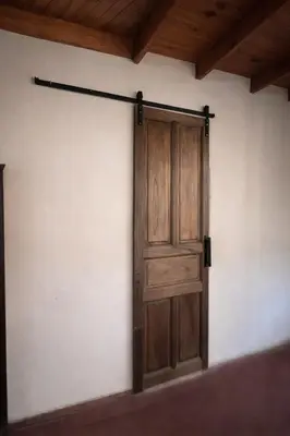 an open wooden door on a white wall at El Bosque de Simba - Cabaña in La Estancia