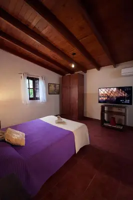 a bedroom with a large bed and a flat screen tv at El Bosque de Simba - Cabaña in La Estancia