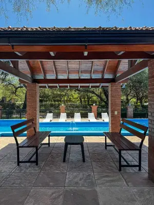 two benches under a pavilion next to a swimming pool at Complejo Udacha - APART in Carpintería