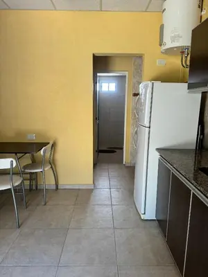 a kitchen with a white refrigerator and a table at Complejo Udacha - APART in Carpintería