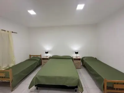 two beds in a room with green sheets at Departamentos Mi Cielo in Villa Cura Brochero