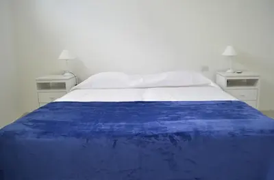 a bed with a blue blanket on top of it at RM Dpto a pocas cuadras del centro in Villa Carlos Paz