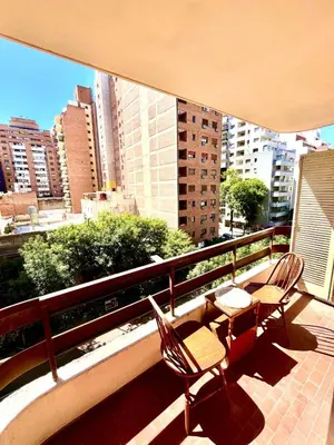 two chairs and tables on a balcony with a view of a city at Departamento amplio 4 personas Zona Nueva Córdoba in Cordoba