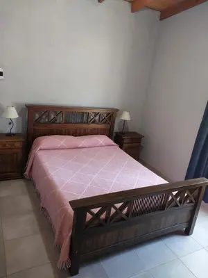 a bedroom with a wooden bed with a pink bedspread at Cabañas San Antonio in Santa Rosa de Calamuchita