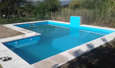 a blue swimming pool with a cross on top at Cabañas San Antonio in Santa Rosa de Calamuchita