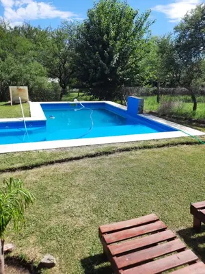 a blue swimming pool in a yard with grass at Cabañas San Antonio in Santa Rosa de Calamuchita