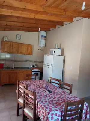 a kitchen with a table and a white refrigerator at Cabañas San Antonio in Santa Rosa de Calamuchita