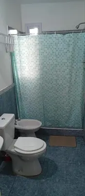 a bathroom with a toilet and a green tiled shower at La Casita De Mabel in Villa Santa Cruz del Lago